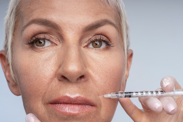 Aged beauty. Attentive female person looking aside while suffering pain during beauty procedure