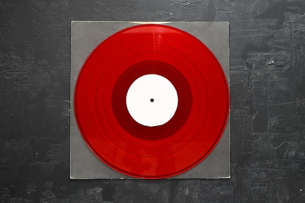 Photo aged black paper cover and red vinyl lp record isolated on stone background