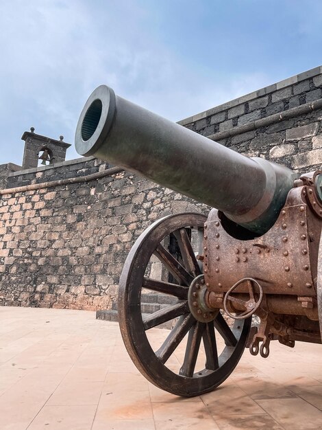 Foto cannone invecchiato vicino al muro di mattoni squallido