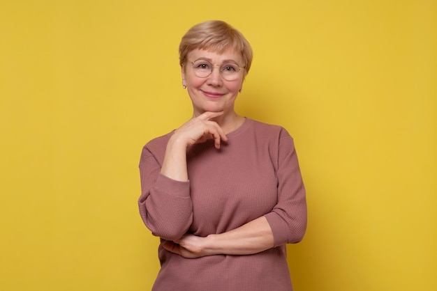 Aged caucasian lady with glasses posing to the camera smiling