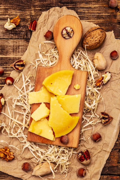 Aged Gouda cheese with pecans walnuts and hazelnuts on old wooden table