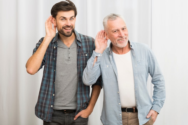 写真 老人と耳の近くの手で若い幸せな男