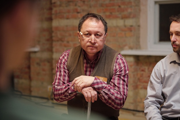 Aged man in eyeglasses and casualwear describing his problem at psychological session