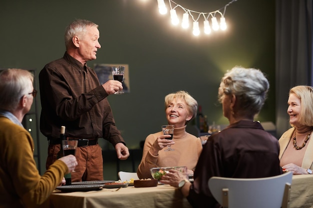 Foto uomo anziano che fa toast durante la cena