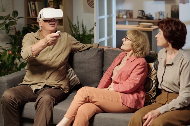 Aged man with vr headset using remote control while making presentation