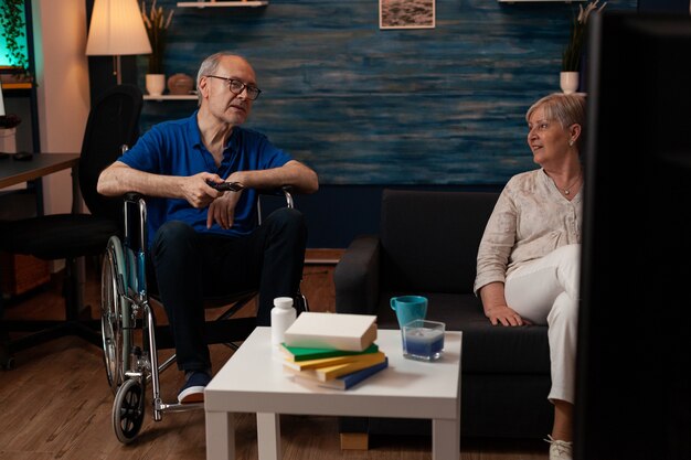 aged married couple relaxing in living room watching tv