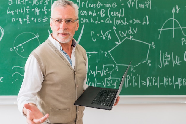 Учитель математики в возрасте стоит с тетрадью | Премиум Фото