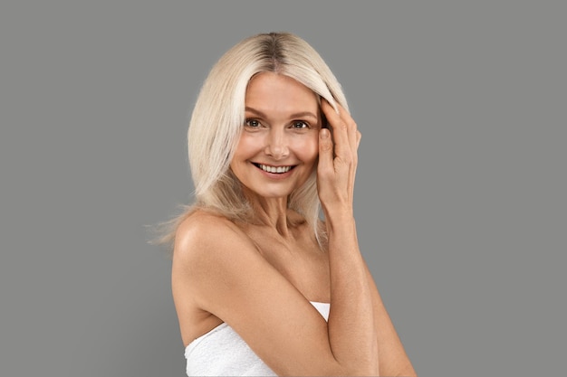 Aged skin care beautiful mature lady touching face and looking at camera