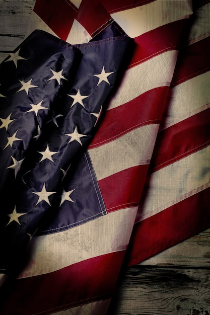 Aged US flag. Creased flag on wooden background. National banner on old table. History had its dark moments.