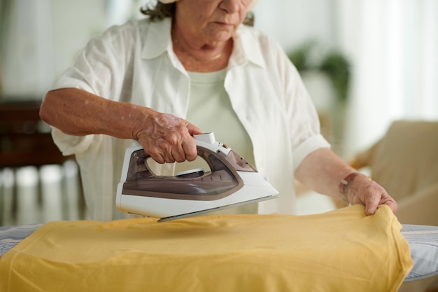 Aged woman steaming tshirt