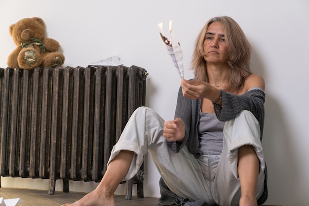 An aged woman with indifference on her face burns an airplane made of a sheet of paper with musical notes