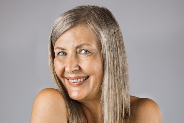 Aged woman with sincere smile posing in studio