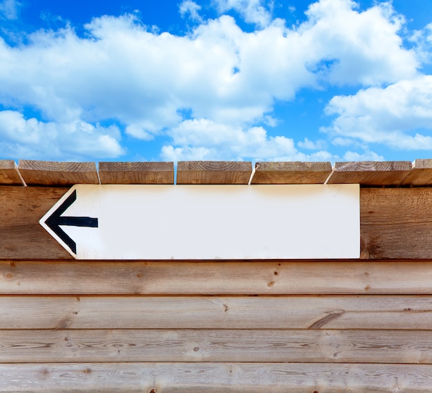 Photo aged wood arrow direction sign on blue sky