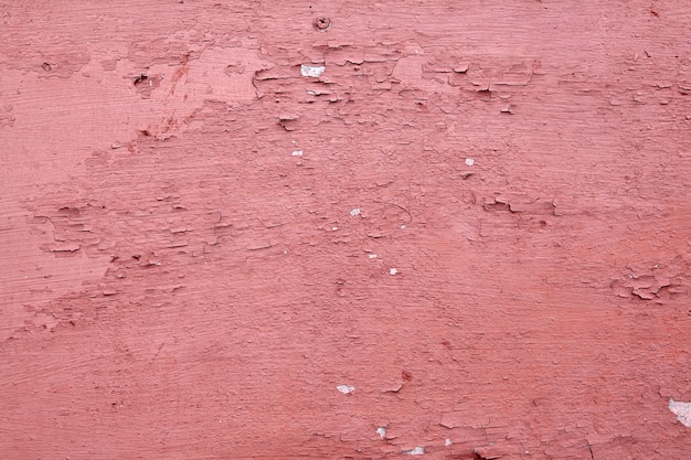 Aged wooden surface with peeling flaky red-brown paint.