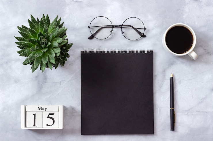 agenda 15 mei. Zwarte notitieblok, kopje koffie, sappig, glazen op marmer
