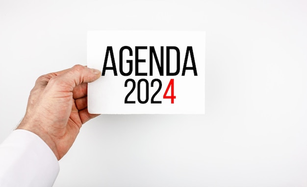 AGENDA 2024 concept text on paper held by a man's hand Agenda 2024 inscription financial