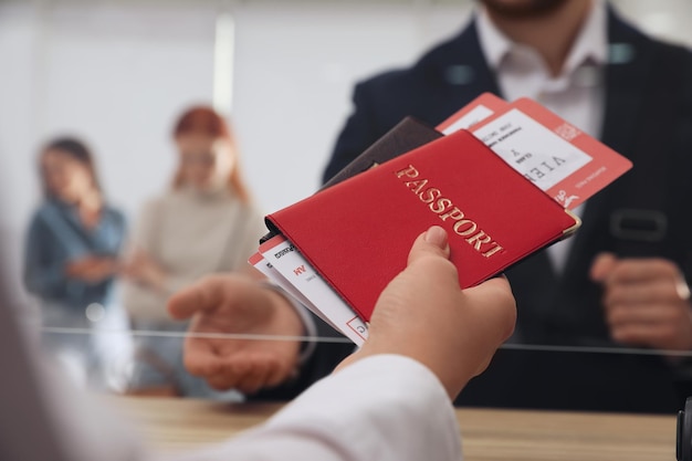 Photo agent giving passports with tickets to client at checkin desk in airport closeup