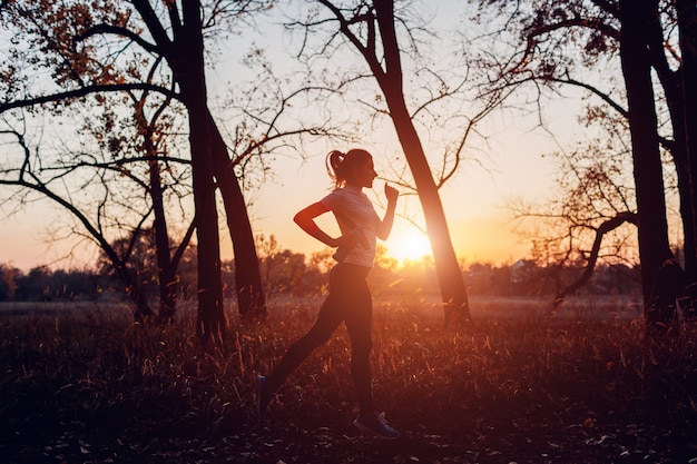 Agent opleiding in de herfstpark, Vrouw die met waterfles bij zonsondergang lopen, Actieve levensstijl