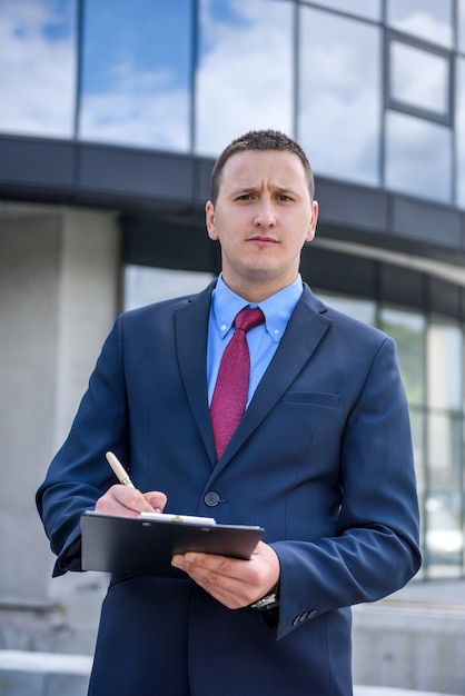 Agent posing with clipboard against new house