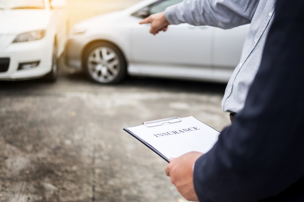 Agent writing on clipboard while examining car after accident