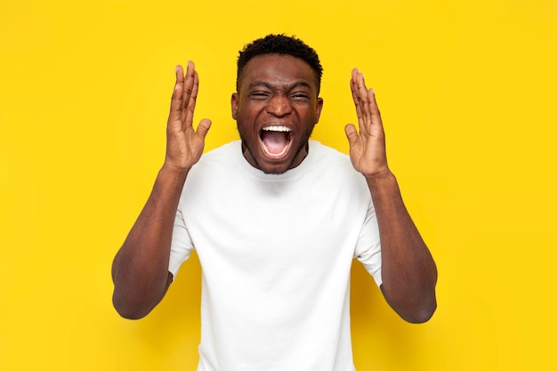 aggressive african american man in white tshirt screams from headache and fatigue