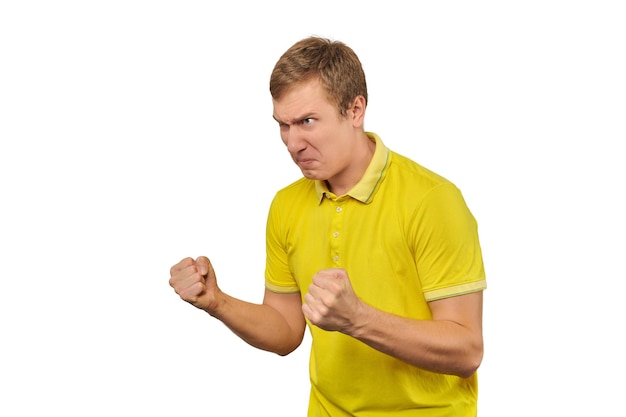 Aggressive angry man in yellow Tshirt ready to fight with fists isolated on white background