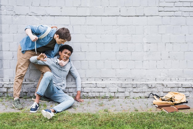 Aggressive boy in shirt bulling going to punch african american boy in hoodie