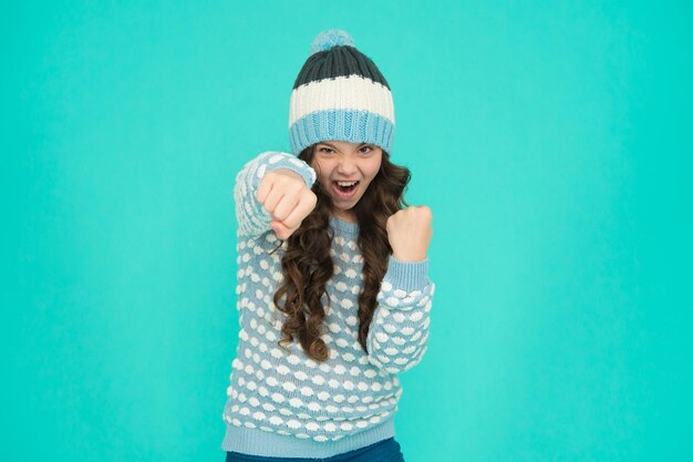 Aggressive child warming up teenager in knitted hat and sweater childhood activity