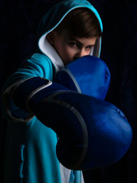 Foto bambino aggressivo che indossa guantoni da boxe illuminazione lowkey