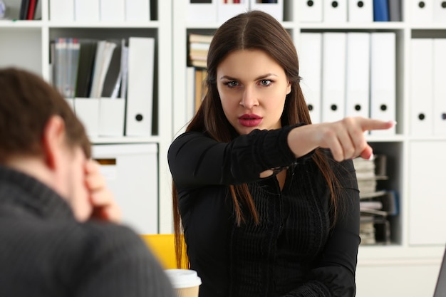 Фото Агрессивная женщина-босс указывает рукой, чтобы уйти, увольняя грустного сотрудника