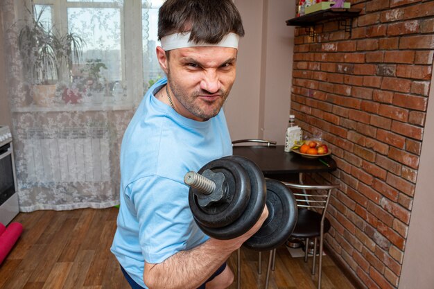 Aggressive funny emotional man holding dumbbells