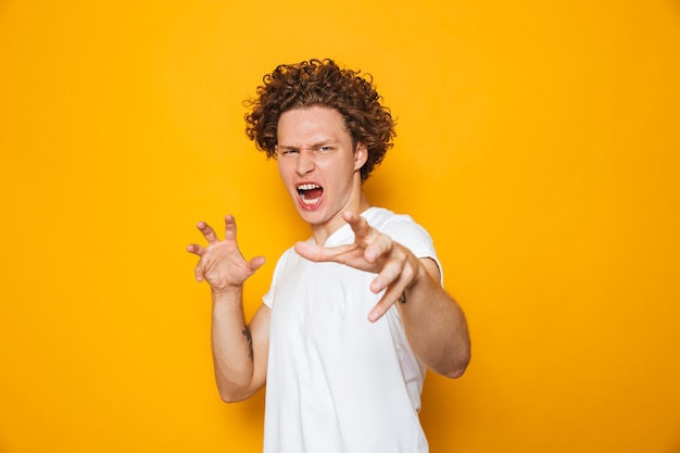 Uomo aggressivo in maglietta casual che grida e che gesturing alla macchina fotografica