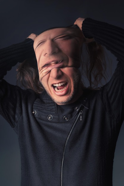 Aggressive man removing mask against gray background