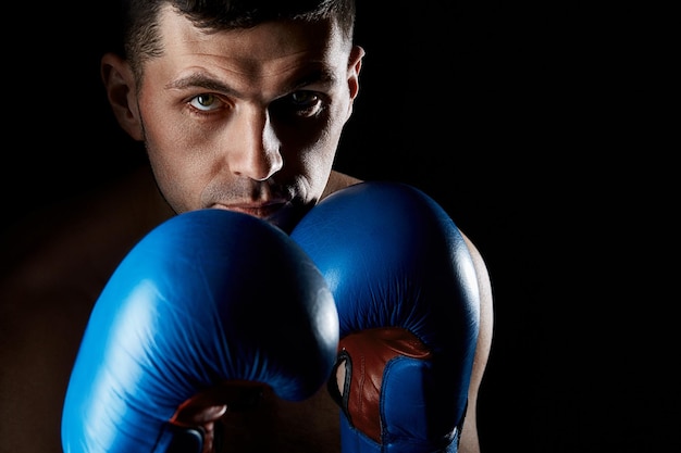 Combattente muscolare aggressivo che si prepara per il combattimento indossando guanti da boxe blu