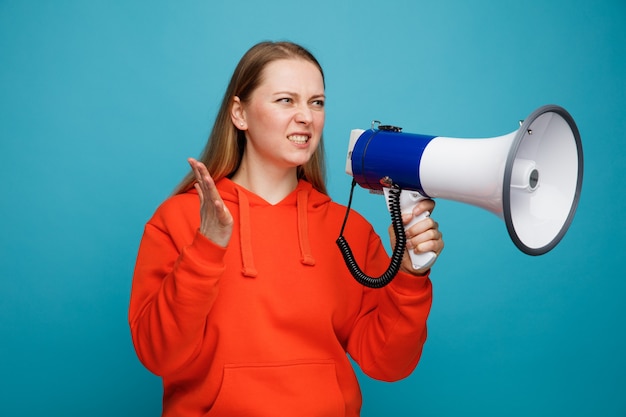 Aggressive young blonde woman holding speaker keeping hand in air looking at side 