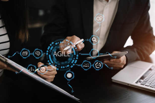 Agile methodologie ontwikkelingsconcept Business team hand met behulp van laptopcomputer en tablet met virtueel scherm agile pictogram op moderne kantoor digitale technologie concept
