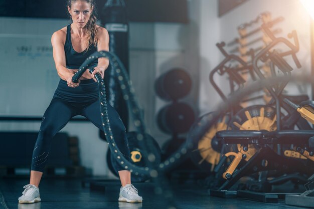 Photo agility training woman exercising with rope in a gym