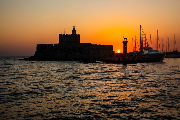 Foto agios nikolaos-fort aan de mandraki-haven van rhodos griekenland in de schemering