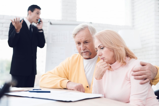 An agitated couple of old people at a reception with a realtor.