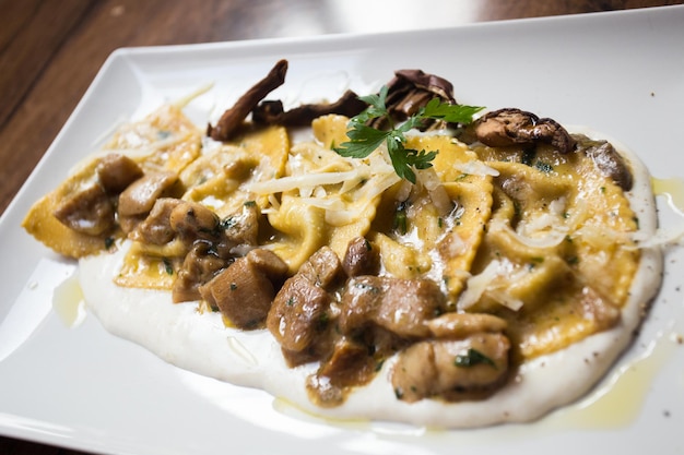 Agnolotti pasta gevuld met vlees gekookt met saus en champignons. Traditioneel Italiaans recept.