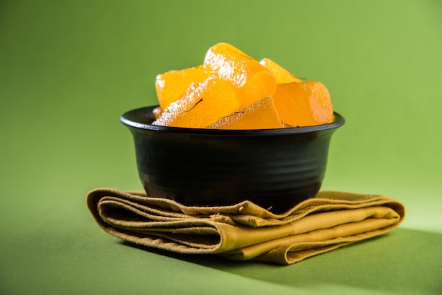 Agra's Shahi Petha - is a sweet candy made using Pumpkin Pieces dipped in sugar syrup with saffron toppings. Served in a plate over moody background. selective focus