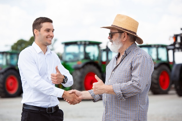 Accordo agricoltore professionista con una moderna mietitrebbia alla luce del sole al lavoro