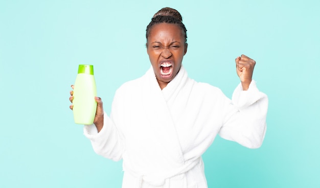 Agressief schreeuwen met een boze uitdrukking in een badjas en een shampoo in de hand