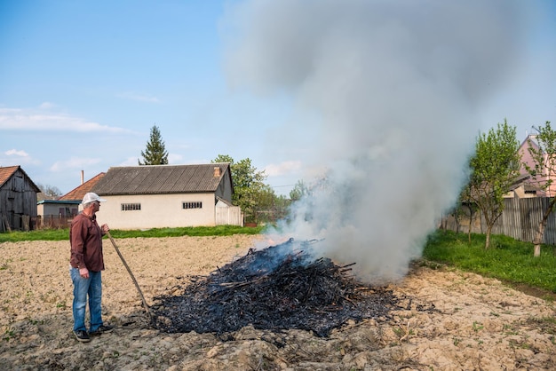 Agricultural concept. Work in the garden. Farmer burning dried branches. Spring time