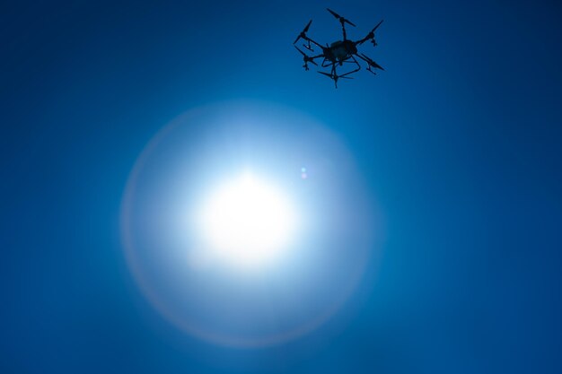 Agricultural drone for fertilizers and pesticides in the sky. silhouette in front of the sun. modern agriculture and innovation.