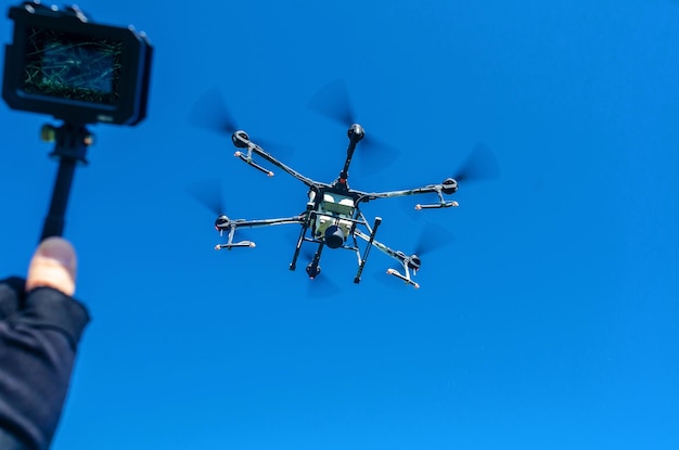 青空を背景に飛行中の農業用ドローン 新技術を散布するフィールド