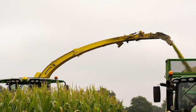 Foto macchinari agricoli trattore e elicottero durante la raccolta del mais