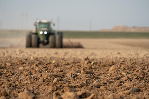 Agricultural machinery works in the field A tractor with a plow cultivates the land before sowing wheat and other cereals Soft focus plowed ground closeup Empty space for inserting text