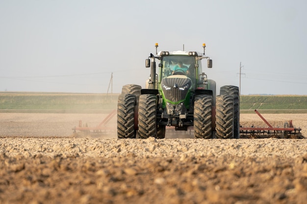 Agricultural machinery works in the field A tractor with a plow and a cultivator cultivates the land before sowing wheat and other cereals The farmer plows the land very nicely and carefully