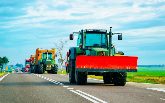 Agricultural Tractor with trailer in road. Farm vehicle van at work on driveway. European transport.  Countryside transportation on highway.